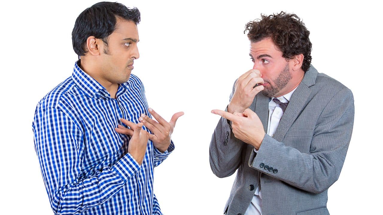 man pointing at another man while holding nose to blame him for bad breath